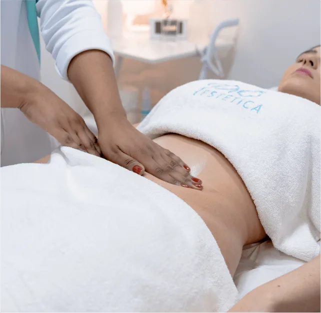 Profissional da Pró Estética fazendo massagem no abdômen de uma cliente deitada na maca.